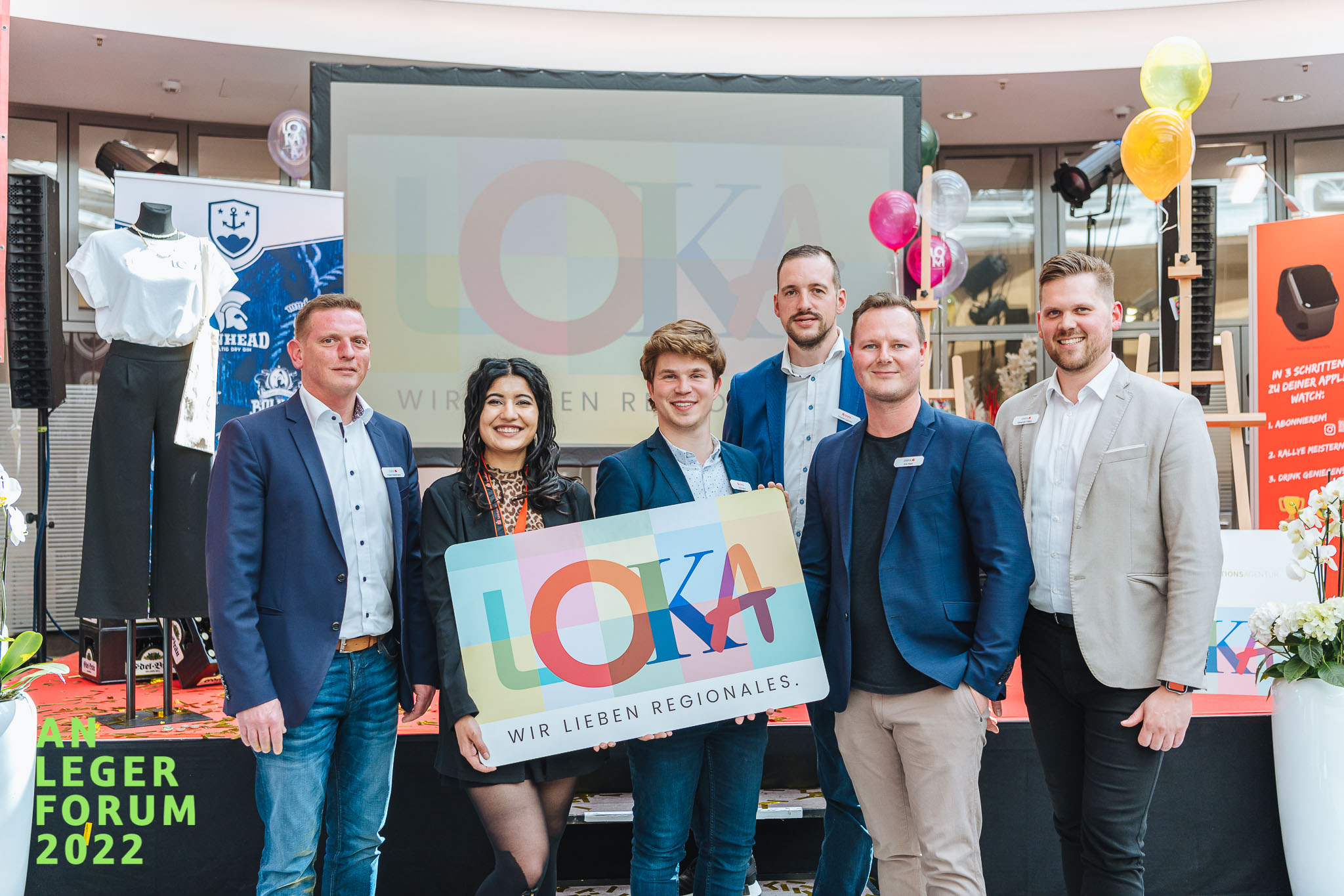 Das Foto zeigt das LOKA Team, zwei von ihnen halten eine große LOKA Karte in der Hand.